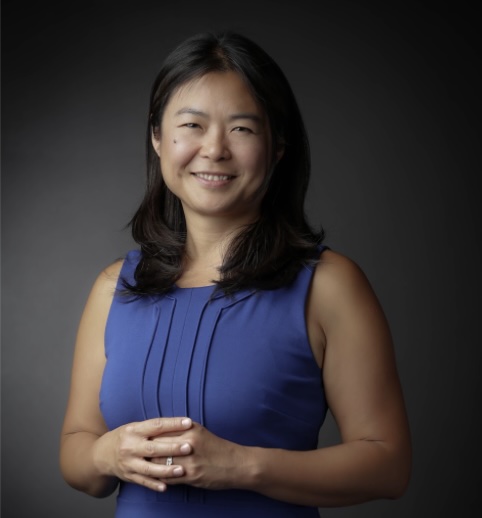 Woman with dark hair and blue dress smiling